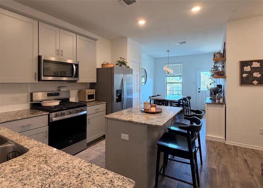 Kitchen with stainless steel appliances, a center island, backsplash, gray cabinetry, and recessed lighting Kitchen with stainless steel appliances, a center island, backsplash, gray cabinetry, and recessed lighting