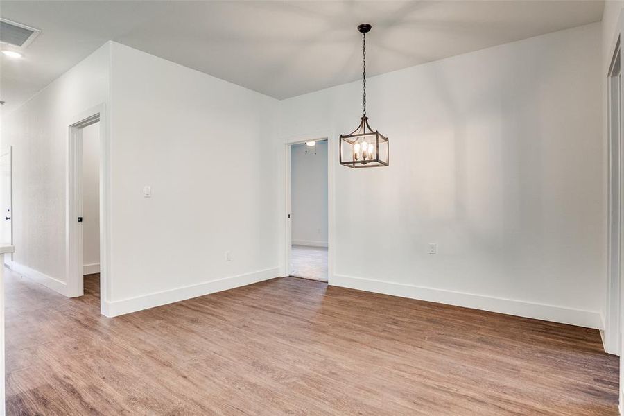 Unfurnished dining area featuring light wood-style flooring and a chandelier