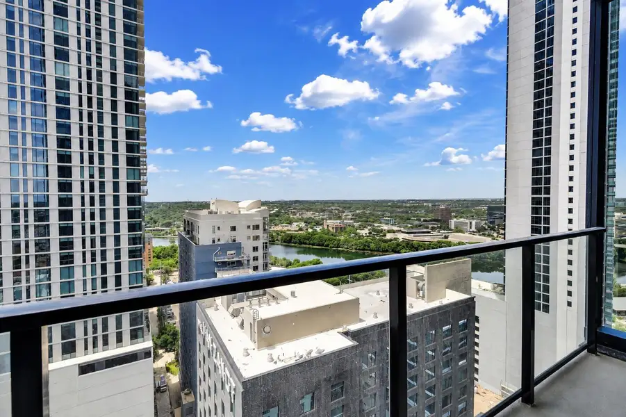 Panoramic city and river vistas unfold from a high-rise balcony under blue skies. Panoramic city and river vistas unfold from a high-rise balcony under blue skies.