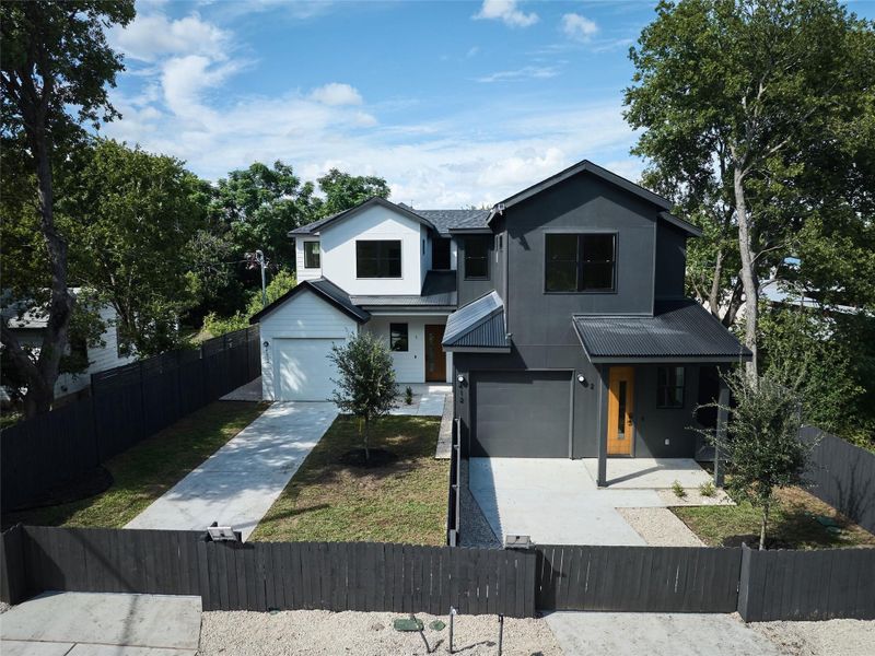 Traditional-style home featuring a metal roof, a fenced front yard, driveway, a garage, and covered porch Traditional-style home featuring a metal roof, a fenced front yard, driveway, a garage, and covered porch