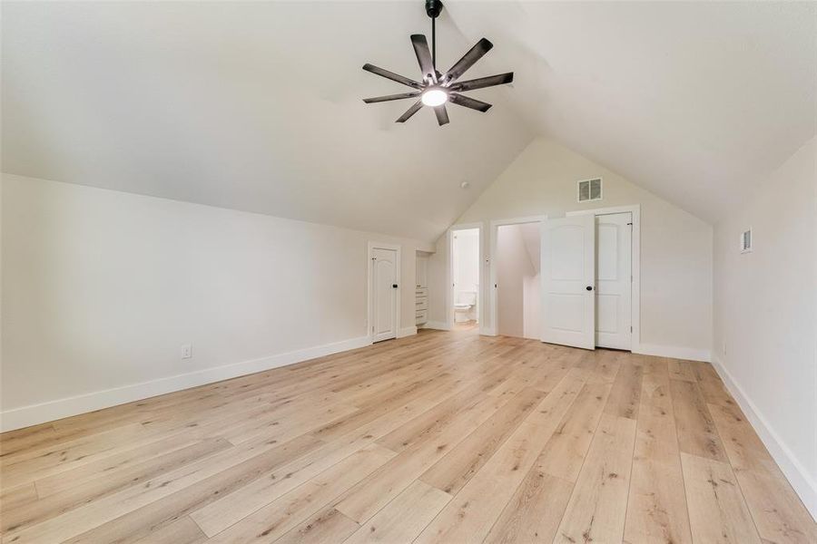 Vaulted ceiling room featuring wood-finish flooring, a modern ceiling fan, and white trim