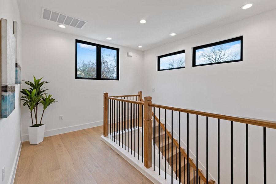 Hallway featuring light wood-style floors, an upstairs landing, recessed lighting, and baseboards