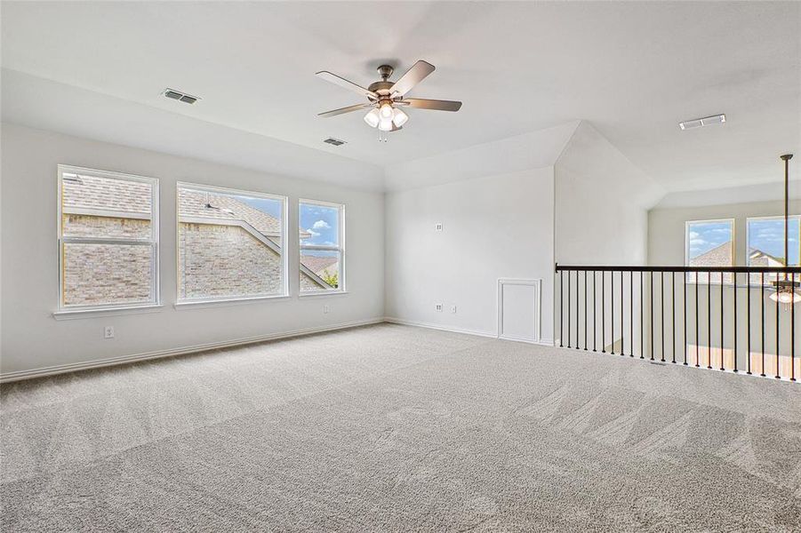 Unfurnished room with ceiling fan, plenty of natural light, and carpet flooring