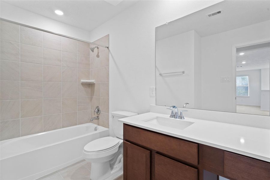 The secondary bathroom showcases tile flooring, a bath/shower combo with tile surround, a vanity with knee space and stunning light countertop, a mirror, sleek fixtures, and contemporary finishes throughout. The secondary bathroom showcases tile flooring, a bath/shower combo with tile surround, a vanity with knee space and stunning light countertop, a mirror, sleek fixtures, and contemporary finishes throughout.