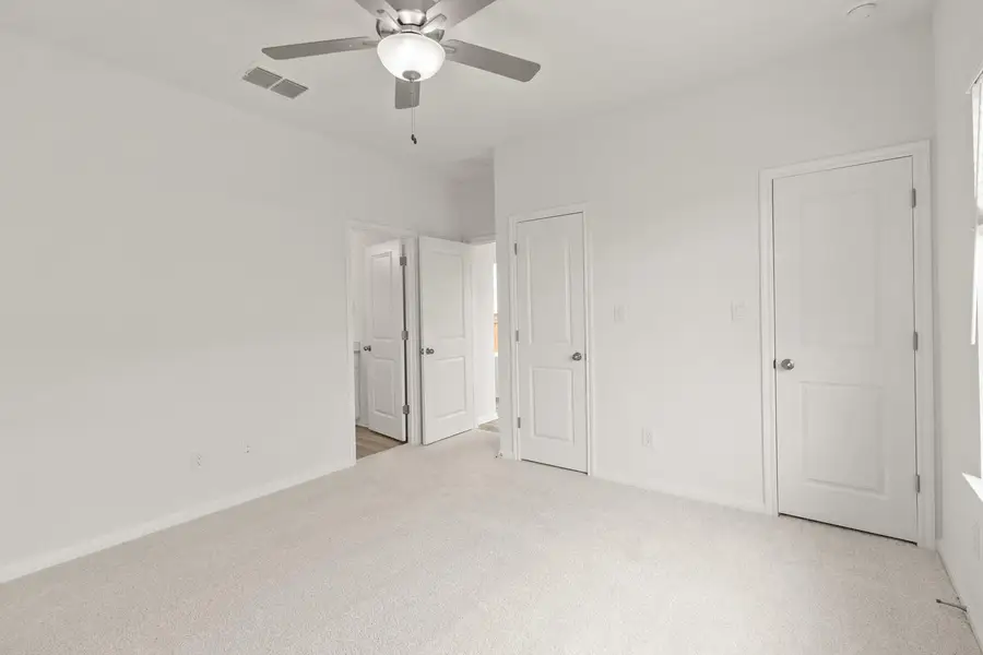 Unfurnished bedroom with light colored carpet and ceiling fan