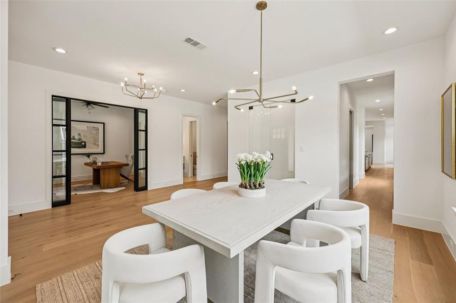 Spacious dining area featuring wood-finish flooring, recessed lighting, and a contemporary chandelier