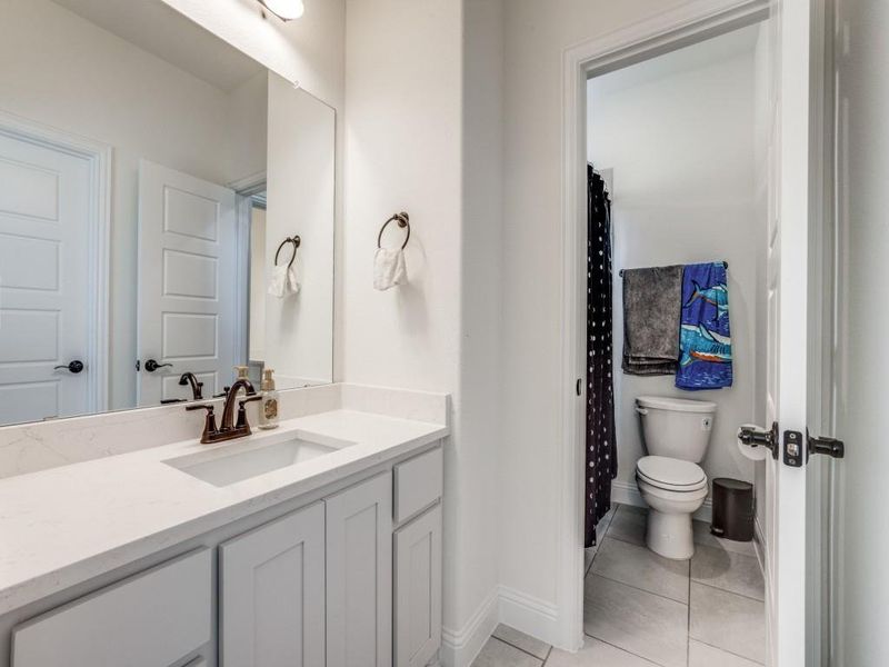 Full bathroom featuring vanity, tile patterned flooring, baseboards, and toilet Full bathroom featuring vanity, tile patterned flooring, baseboards, and toilet