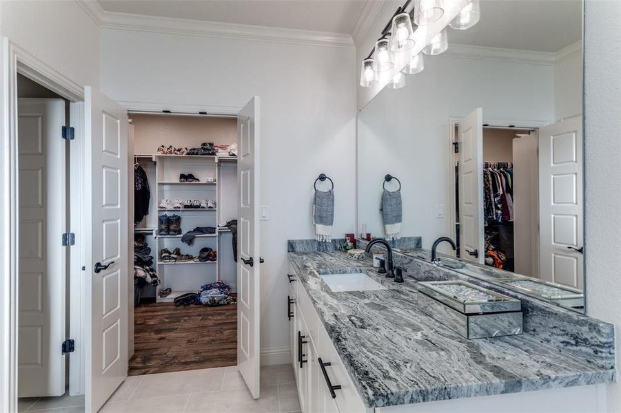 Full bathroom with a spacious closet, vanity, tile patterned floors, and ornamental molding