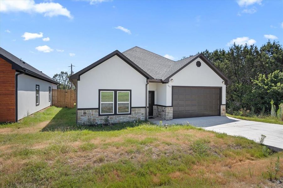 View of front facade featuring a garage and a front lawn