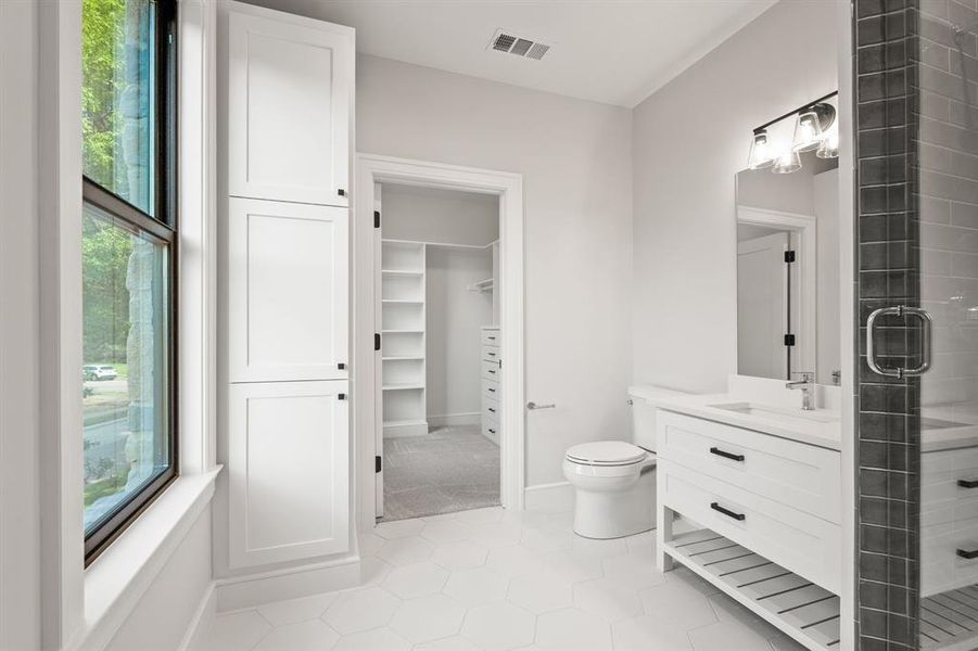 Full bath featuring plenty of natural light, a shower stall, vanity, and a walk in closet Full bath featuring plenty of natural light, a shower stall, vanity, and a walk in closet
