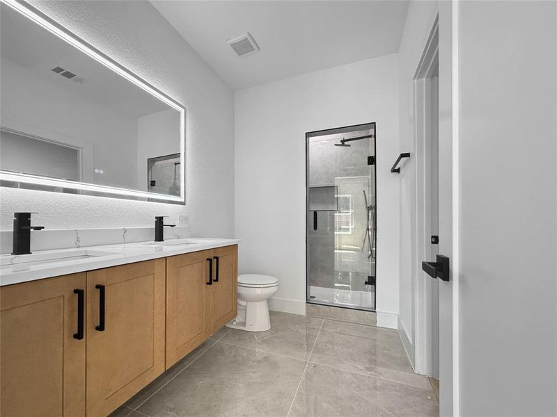 Bathroom with a stall shower, double vanity, and light tile patterned floors