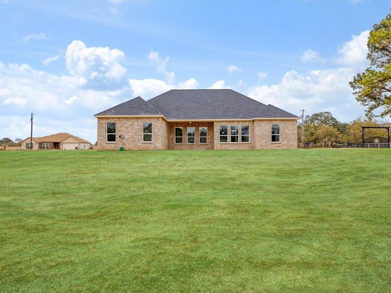 Rear view of property featuring a yard, a shingled roof, brick siding, and a patio area Rear view of property featuring a yard, a shingled roof, brick siding, and a patio area