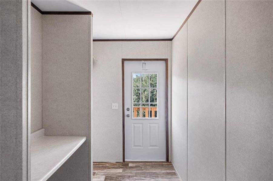 Doorway to outside with ornamental molding and light wood-type flooring