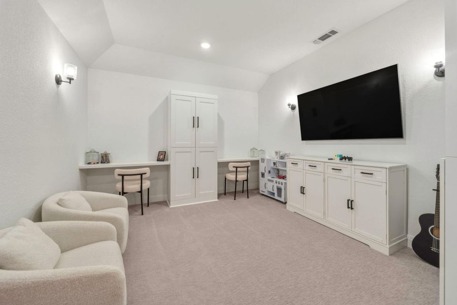 Spacious bonus room featuring sloped ceilings, recessed lighting, wall sconces, built-in desk areas, and a large built-in storage cabinets