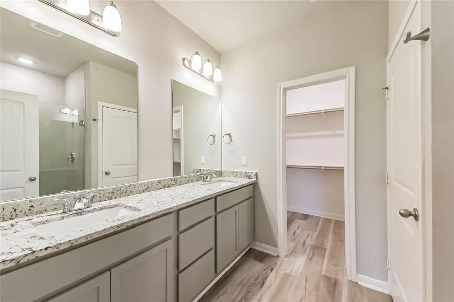 The primary bathroom features modern finishes, a spacious shower, and granite countertops with dual sinks.