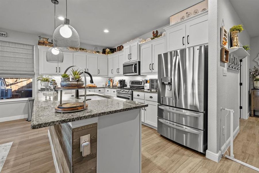 Kitchen featuring stone counters, sink, white cabinets, and appliances with stainless steel finishes