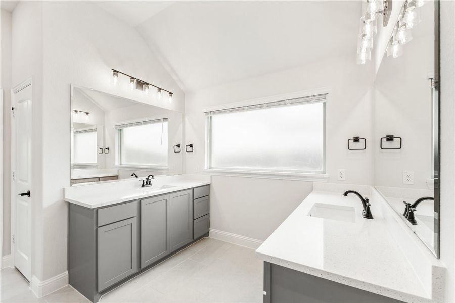 Bathroom with dual gray vanities, white quartz countertops, vaulted ceiling, and soaking tub Bathroom with dual gray vanities, white quartz countertops, vaulted ceiling, and soaking tub