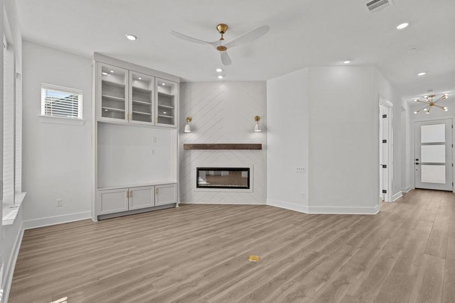 Unfurnished living room with a large fireplace, light wood-type flooring, a ceiling fan, and recessed lighting
