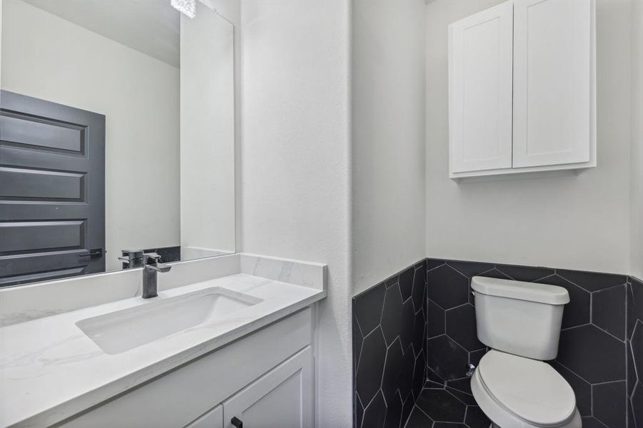 Bathroom with vanity, toilet, and tile walls