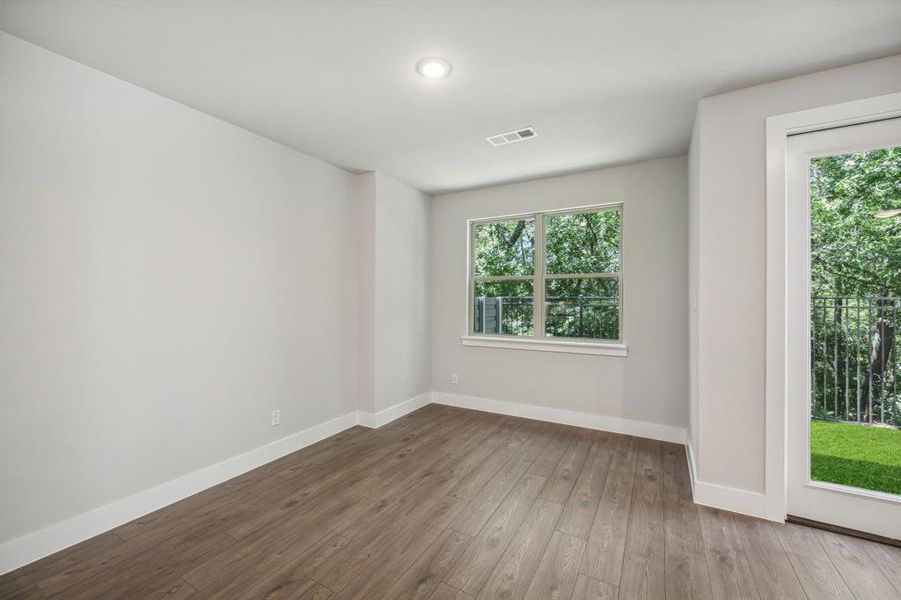 Empty room with hardwood / wood-style flooring and plenty of natural light