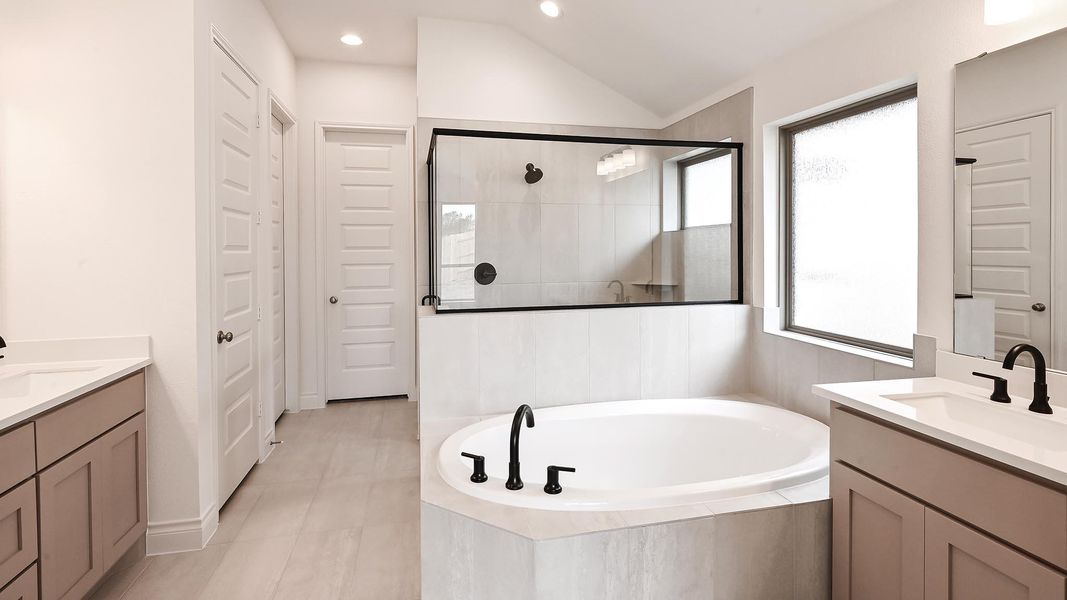 Full bath featuring plenty of natural light, two vanities, tiled shower, lofted ceiling, and recessed lighting Full bath featuring plenty of natural light, two vanities, tiled shower, lofted ceiling, and recessed lighting