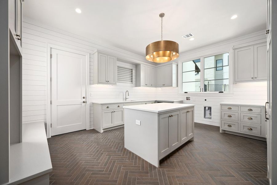 A well-appointed laundry room boasts a central island and patterned flooring, offering both style and utility.