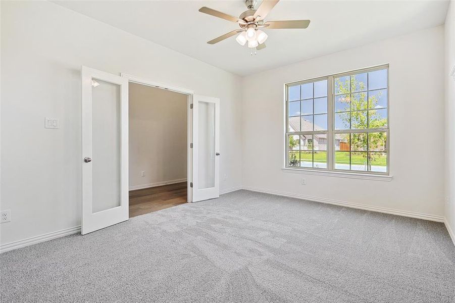 Carpeted spare room with ceiling fan and french doors