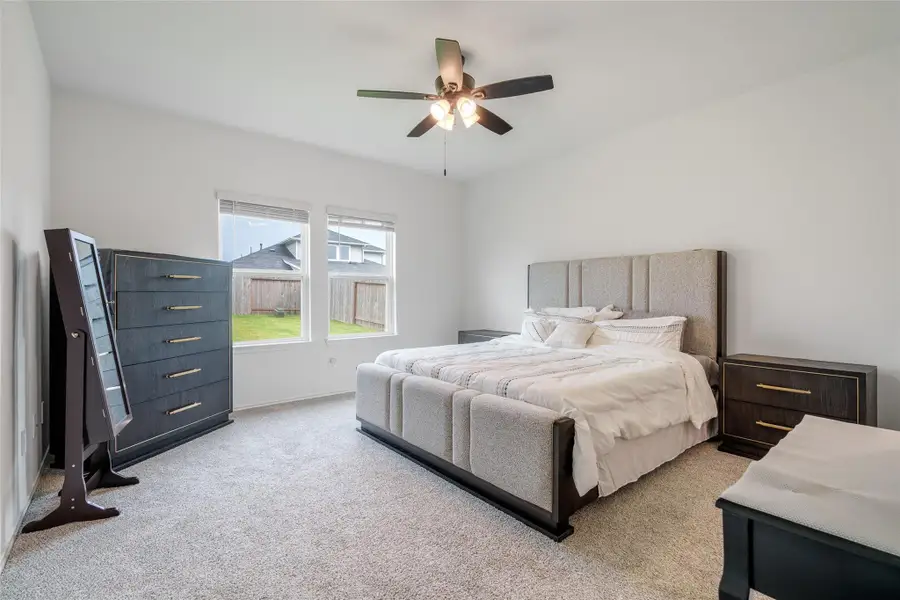 Retreat to the serene primary bedroom, featuring plush carpet flooring, two large windows that fill the space with natural light, and a stylish dark-stained ceiling fan for added comfort and charm. Retreat to the serene primary bedroom, featuring plush carpet flooring, two large windows that fill the space with natural light, and a stylish dark-stained ceiling fan for added comfort and charm.