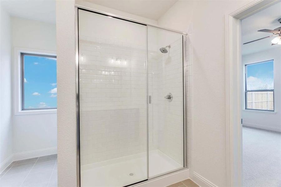 Full bathroom featuring a shower stall and baseboards