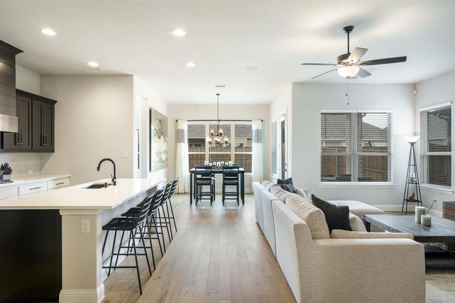 Living room featuring recessed lighting, ceiling fan, light wood-style floors, a chandelier, and baseboards Living room featuring recessed lighting, ceiling fan, light wood-style floors, a chandelier, and baseboards