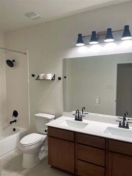 Full bath with double vanity, washtub / shower combination, light tile patterned floors, and a textured wall Full bath with double vanity, washtub / shower combination, light tile patterned floors, and a textured wall