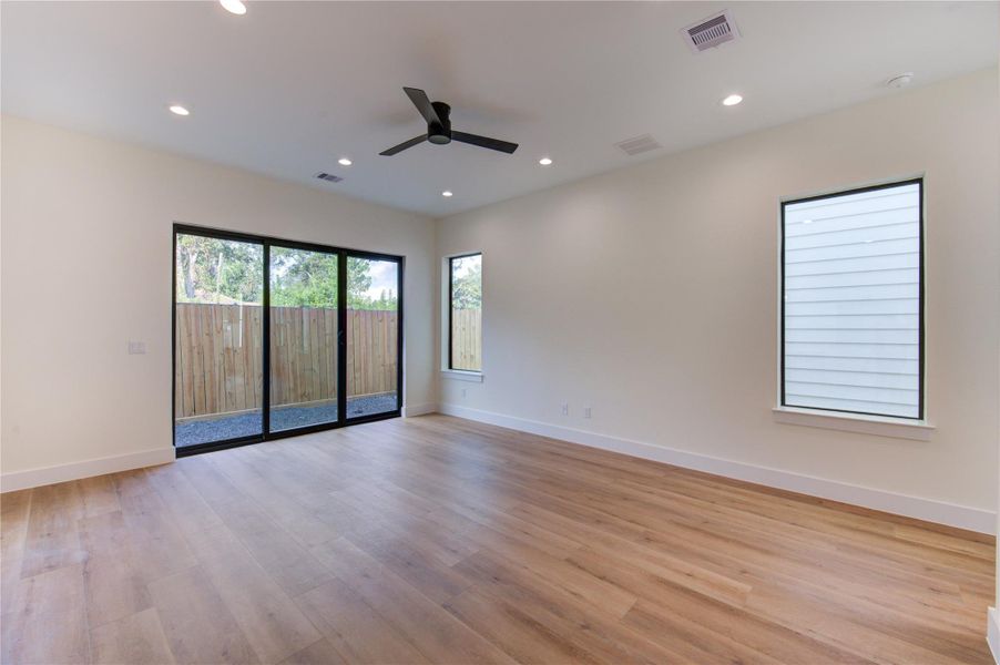 Spacious and bright living area featuring sleek vinyl plank floors, modern recessed lighting, and large windows offering serene outdoor views. Spacious and bright living area featuring sleek vinyl plank floors, modern recessed lighting, and large windows offering serene outdoor views.