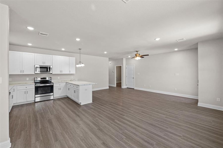 Kitchen with ceiling fan, white cabinets, kitchen peninsula, wood-type flooring, and stainless steel appliances