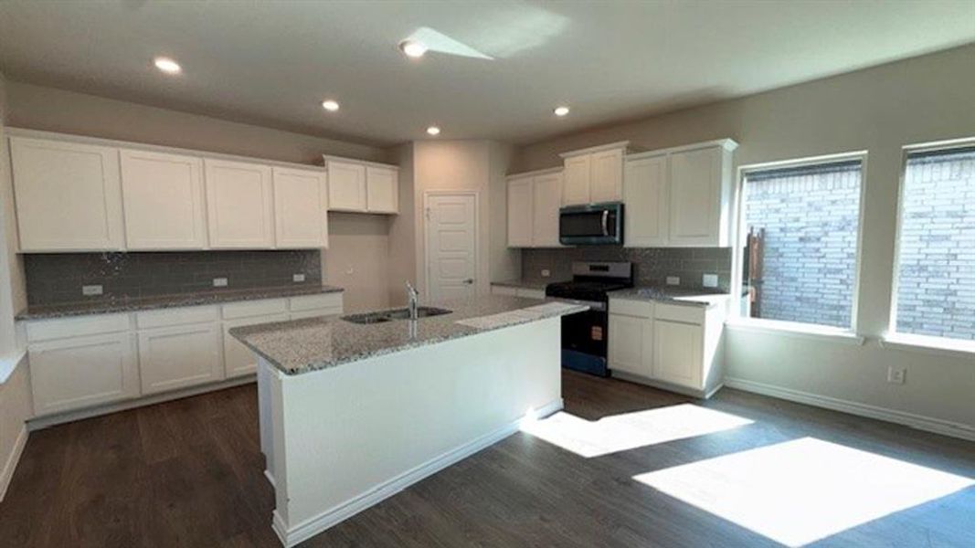 Kitchen with white cabinets, appliances with stainless steel finishes, backsplash, dark wood-type flooring, and an island with sink Kitchen with white cabinets, appliances with stainless steel finishes, backsplash, dark wood-type flooring, and an island with sink