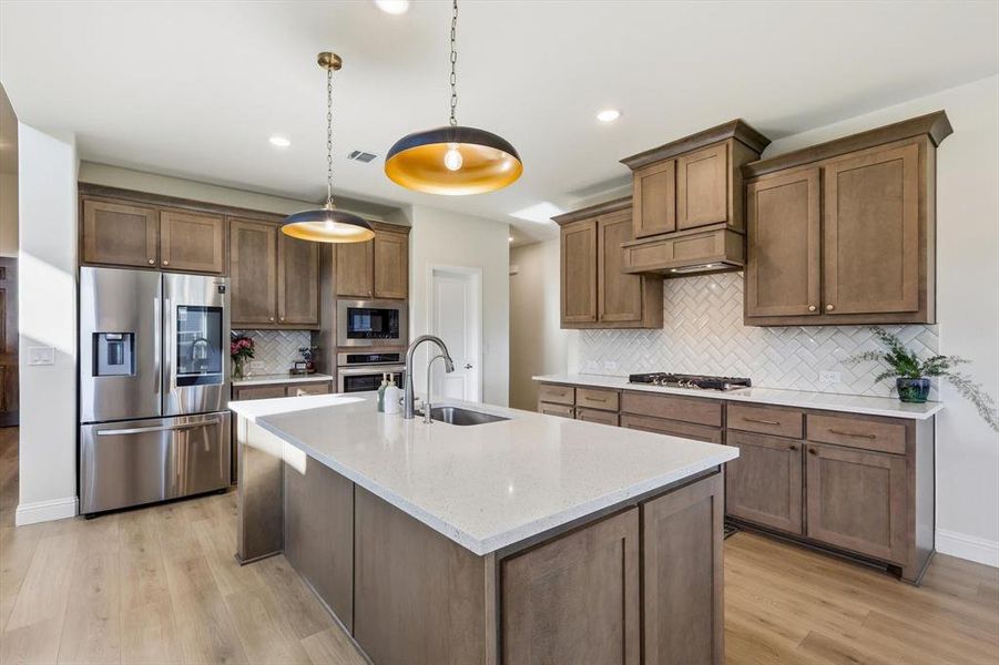 Wow! Modern kitchen featuring a central island with an undermount farmers sink, Granite countertops, stainless steel appliances, Pendant lights and herringbone tile backsplash