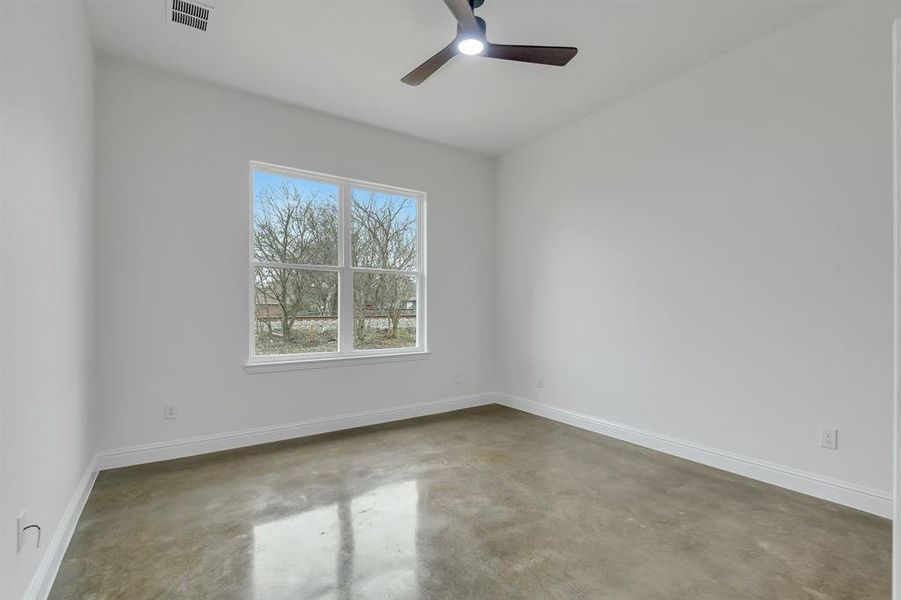 Unfurnished room with finished concrete floors and ceiling fan