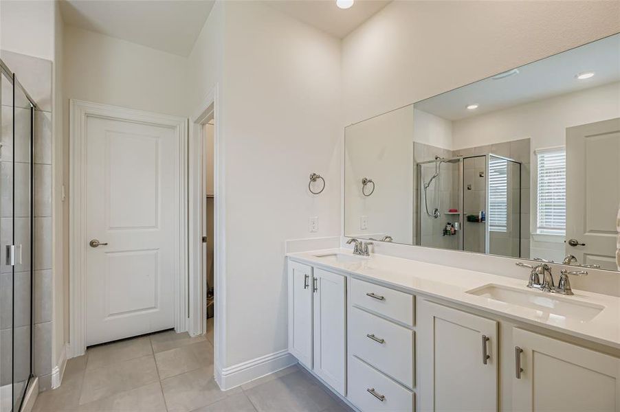 Full bathroom featuring a stall shower, double vanity, light tile patterned flooring, and recessed lighting
