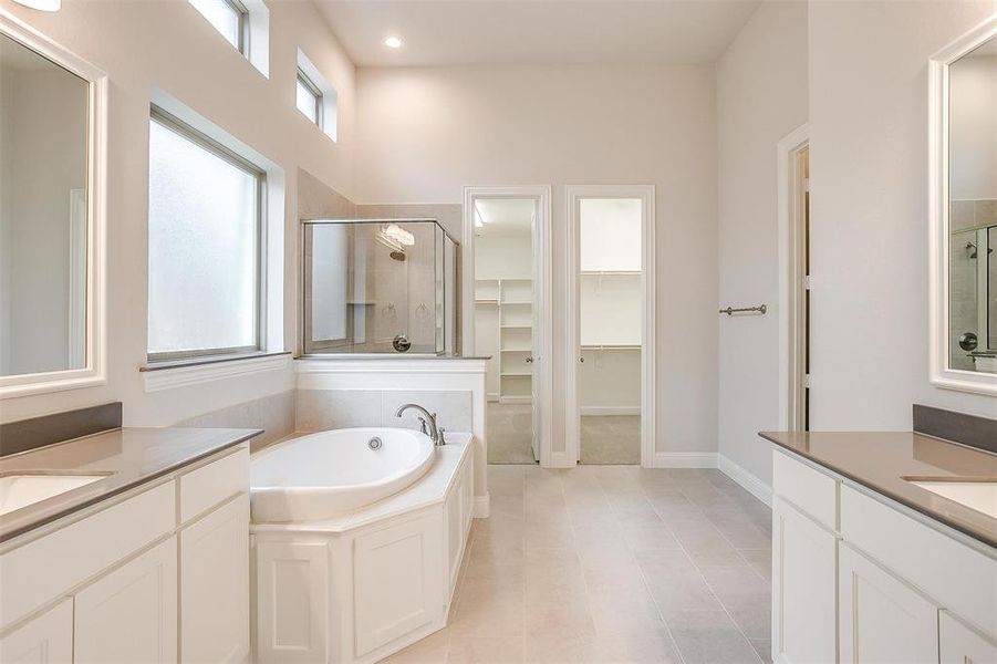 Bathroom featuring vanity, a towering ceiling, tile patterned floors, and separate shower and tub