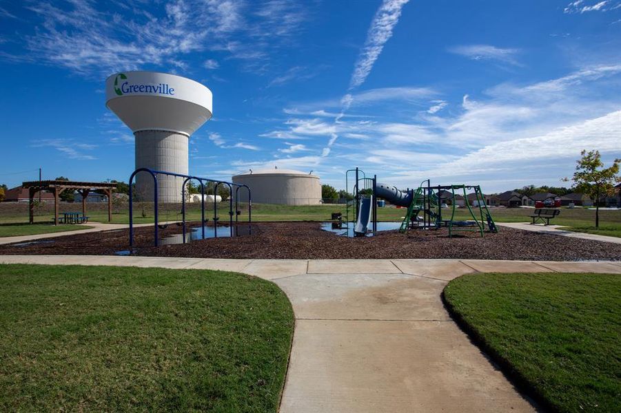 Community playground featuring a slide, swings, and a picnic area under a pergola