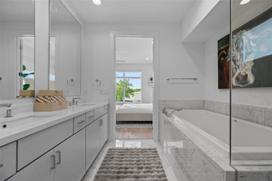 Bathroom featuring a dual vanity with undermount sinks, an expansive countertop, and light gray cabinetry