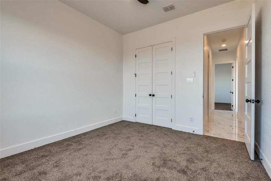 Unfurnished bedroom with a closet, visible vents, carpet flooring, and baseboards