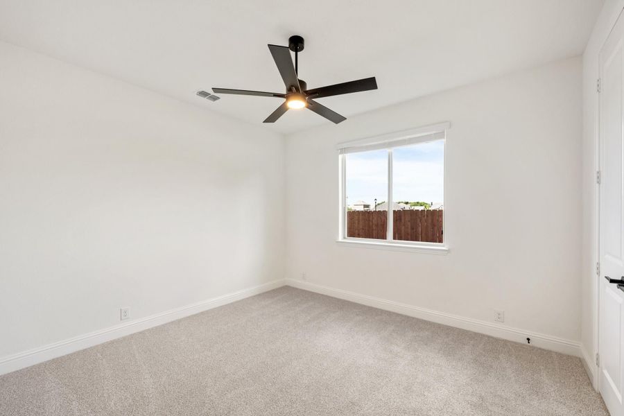 Empty bedroom with carpet flooring, white walls, ceiling fan, and a single window