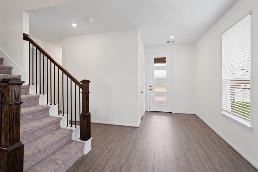 Welcome to your new home at 15711 Autumn Chicory Drive. You are greeted with this beautiful entryway featuring vinyl plank flooring, recessed lighting, large window with privacy blinds, and custom paint.