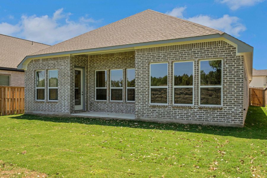 Back of house with a patio, roof with shingles, brick siding, fence, and a lawn