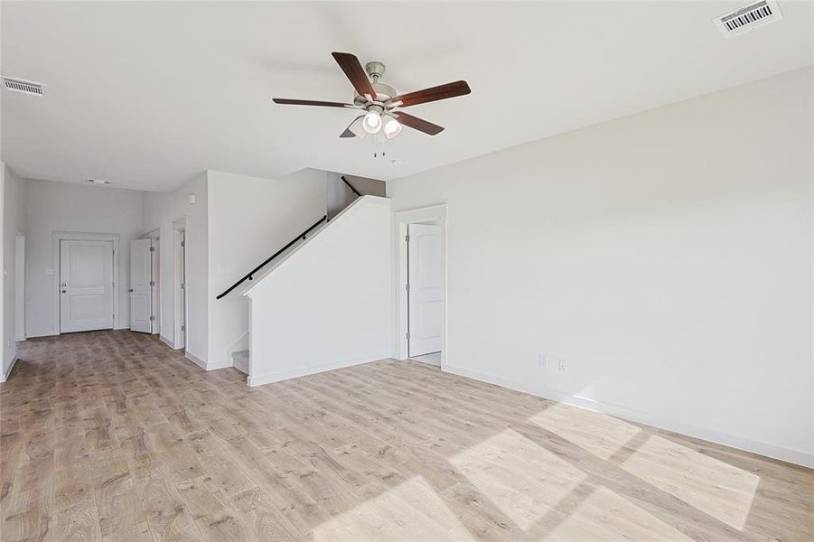 Unfurnished living room featuring ceiling fan and light wood-type flooring