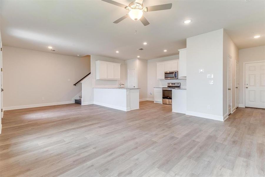 Unfurnished living room featuring ceiling fan and light wood-type flooring