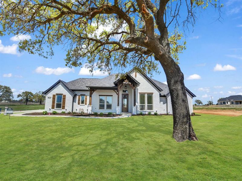 Modern farmhouse featuring brick siding, roof with shingles, and a front lawn Modern farmhouse featuring brick siding, roof with shingles, and a front lawn