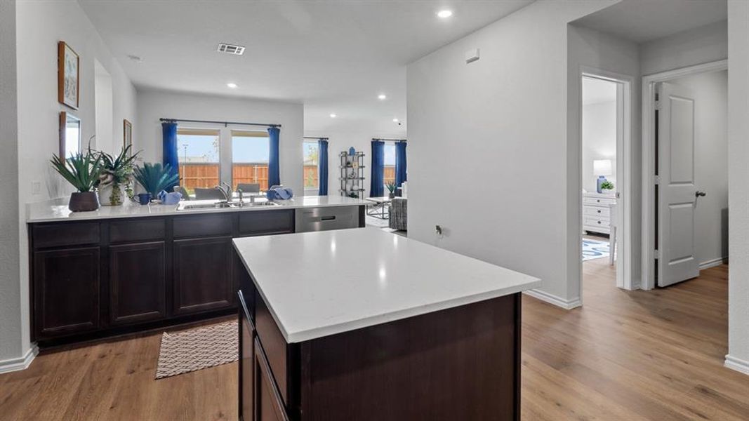 Kitchen featuring a peninsula, a center island, light wood-style flooring, recessed lighting, and dark wood finish cabinets Kitchen featuring a peninsula, a center island, light wood-style flooring, recessed lighting, and dark wood finish cabinets