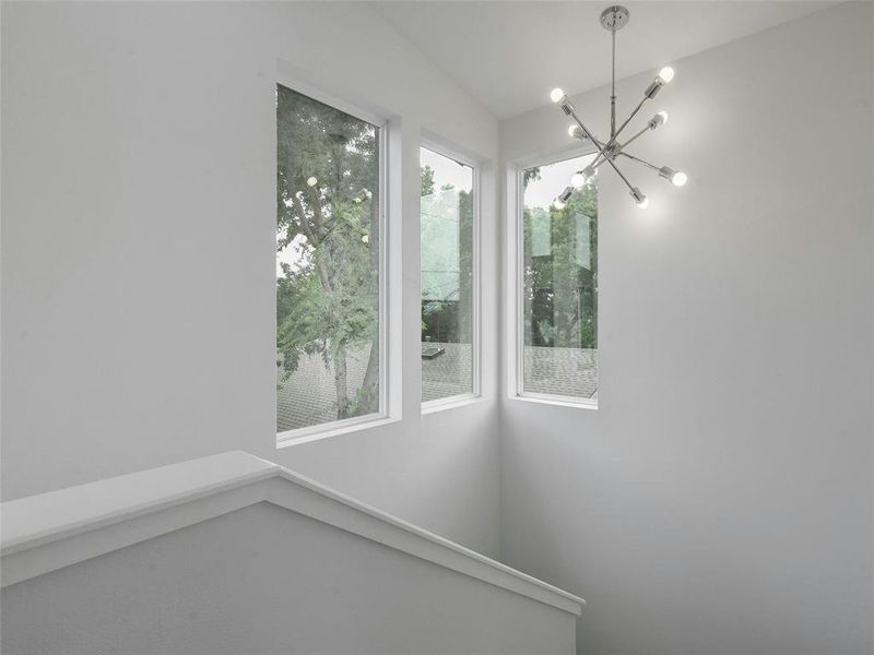 A stunning chandelier graces the space above the staircase, illuminating the path to the upper floor with style and grace.