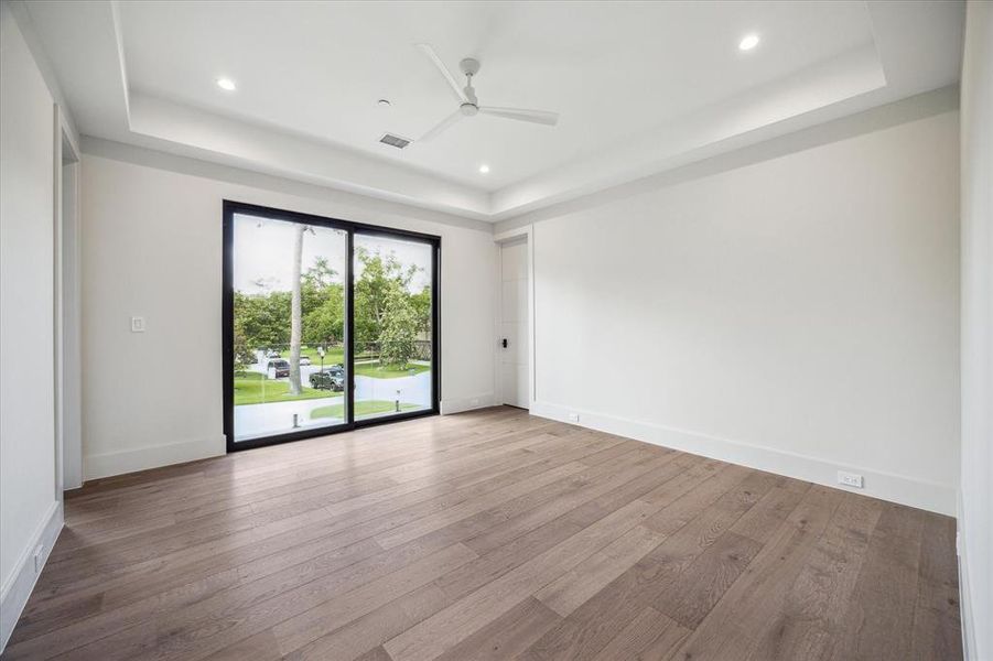 The second-floor Guest Suite No. 2 features a private balcony, an 11' ceiling featuring a tray ceiling design, and neutral designer wall paint, creating an airy and sophisticated atmosphere. It offers convenient access to its ensuite bathroom, ensuring comfort and privacy for guests.